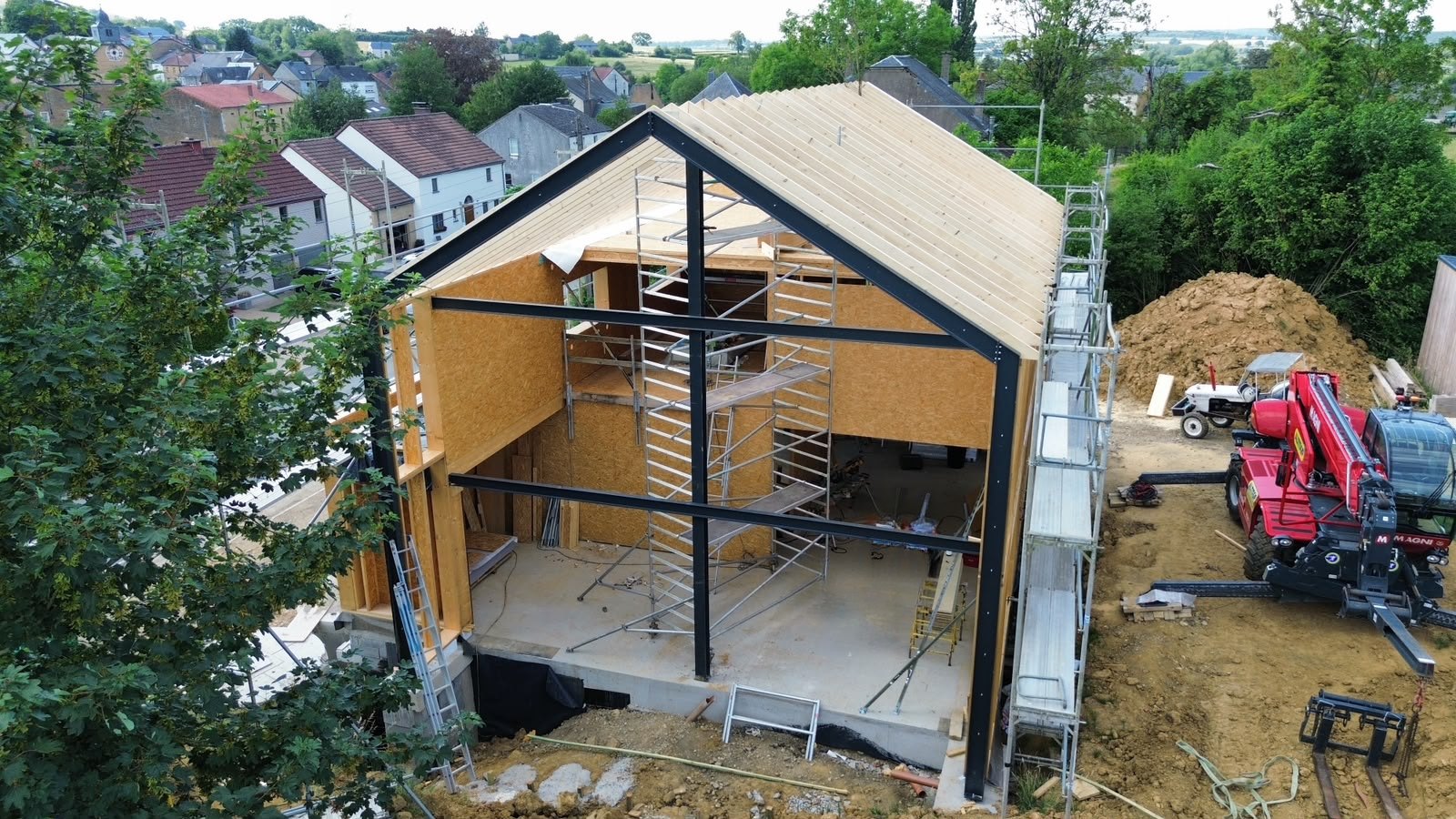 Maison à ossature bois en cours de construction : charpente, panneaux OSB et portique en acier